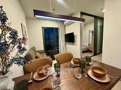 Modern dining area with stylish tableware, open layout to cozy living room and bedroom, perfect for urban living.