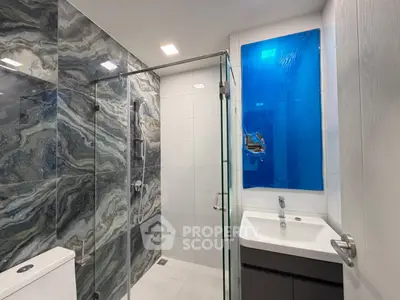 Modern bathroom with elegant marble tiles and glass shower enclosure