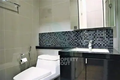 Modern bathroom with sleek design and stylish black tile accents.