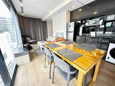 Modern living room with open kitchen, large windows, and stylish furniture in a high-rise apartment.