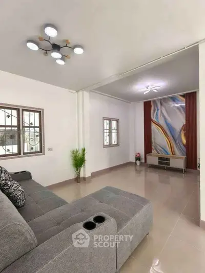 Modern living room with stylish decor and comfortable gray sofa, featuring unique wall art and elegant lighting.