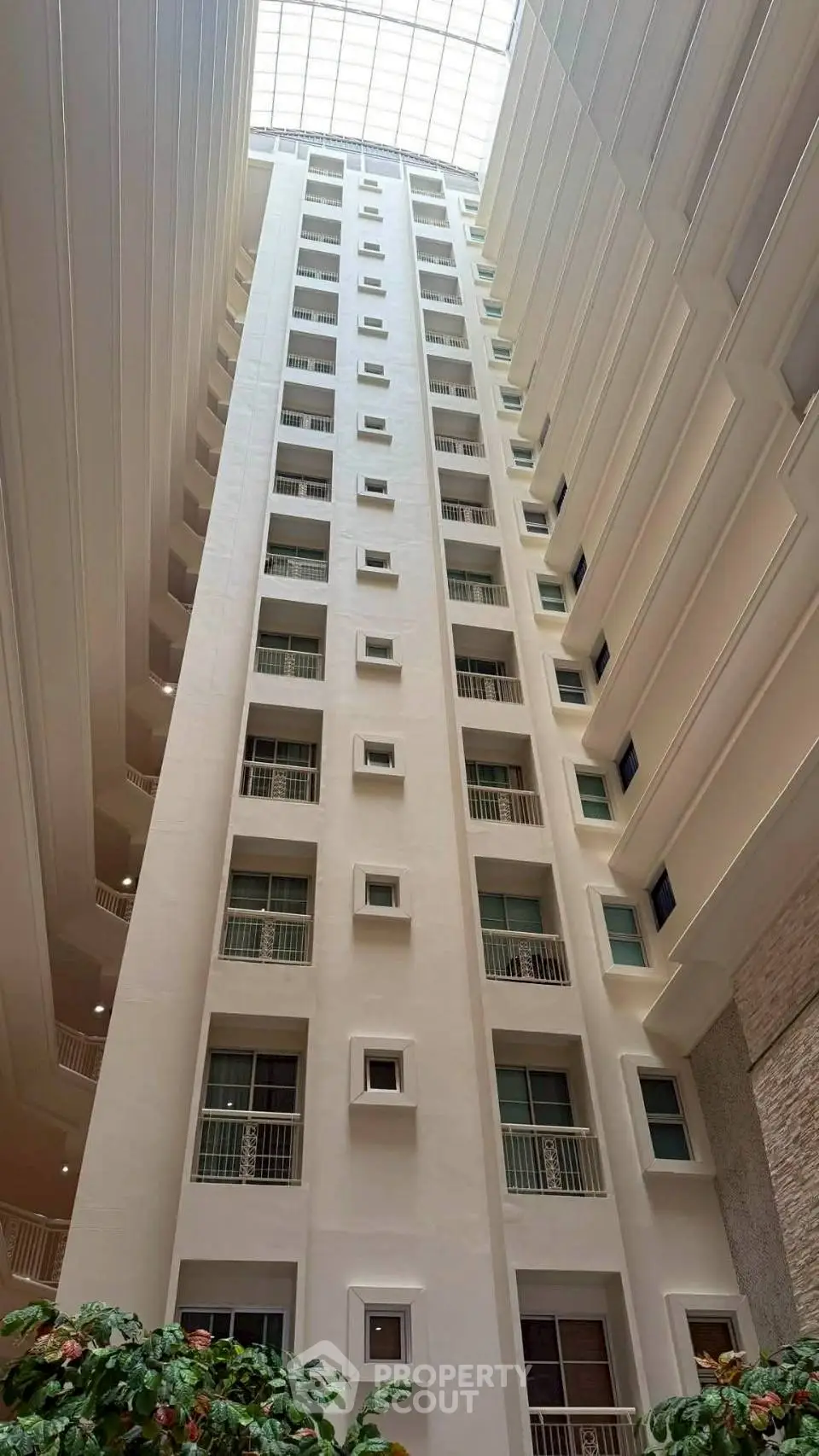 Stunning atrium view of modern high-rise building with natural light and lush greenery.
