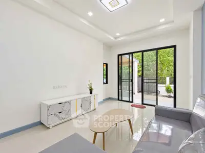 Modern living room with sleek furniture and large glass doors opening to a lush garden view.