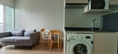 Modern apartment with cozy living area and compact kitchen featuring washing machine.