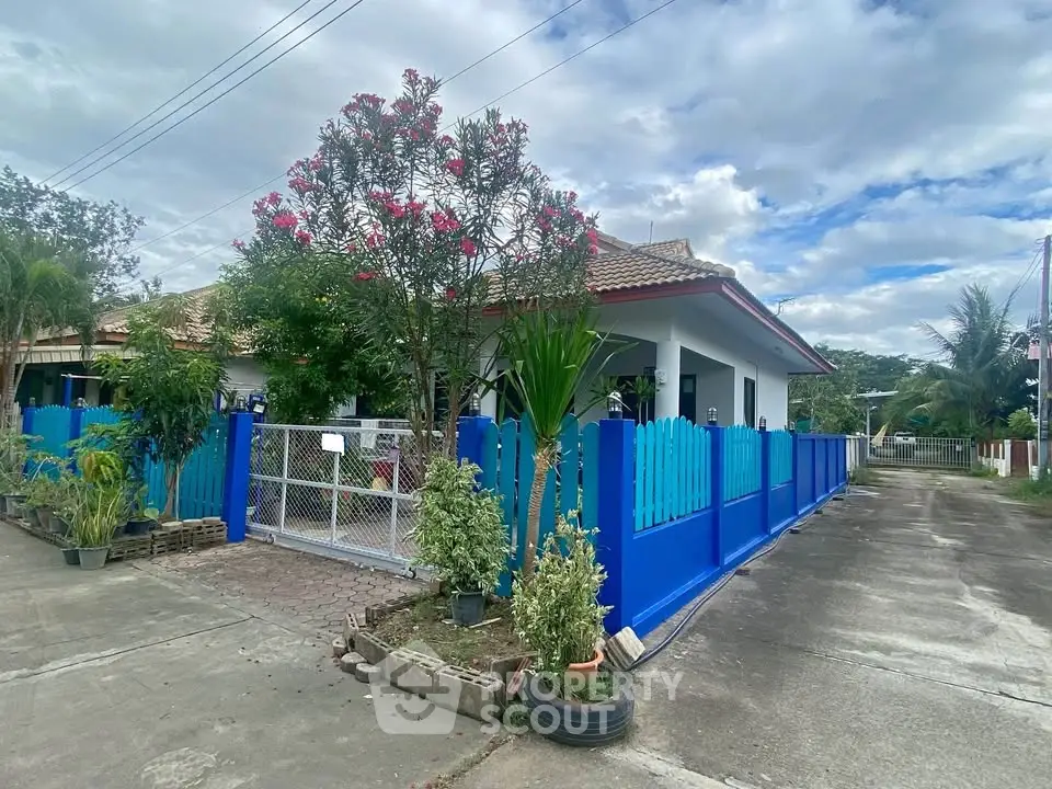 Charming single-story home with vibrant blue fence and lush garden, perfect for serene living.