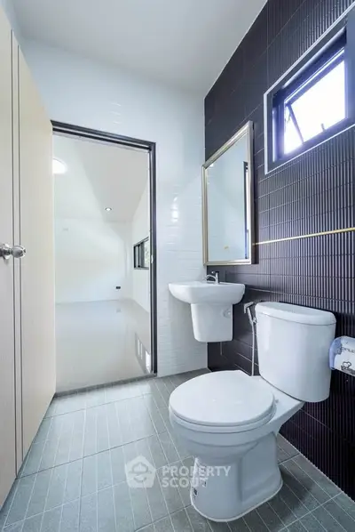 Modern bathroom with sleek design and natural light, featuring a toilet and sink.