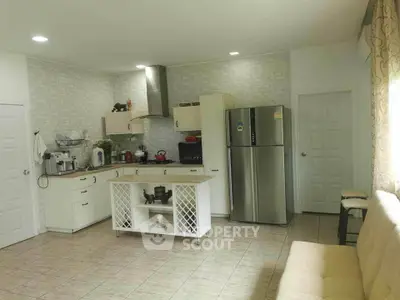 Spacious kitchen with modern appliances and ample counter space, featuring a stylish backsplash and tile flooring, seamlessly opening to a cozy living area.