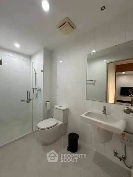 Modern bathroom with glass shower and sleek fixtures in a contemporary apartment.