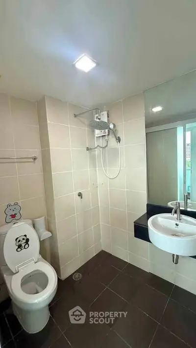 Modern bathroom with shower, toilet, and sleek sink in a tiled setting.