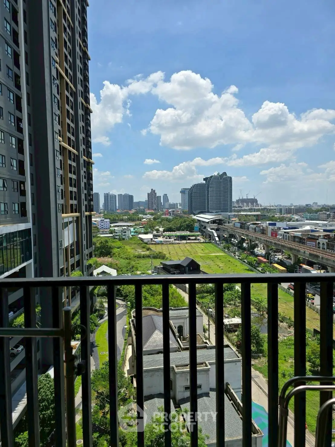 Stunning cityscape view from a high-rise balcony with lush greenery and modern architecture.