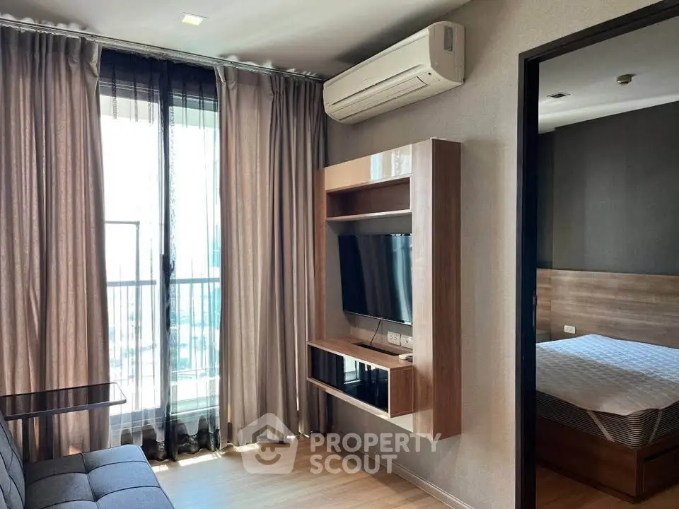 Modern living room with TV and air conditioning, adjacent to a cozy bedroom with natural light.
