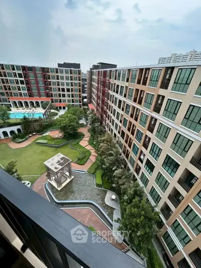 Stunning aerial view of modern apartment complex with lush gardens and pool, perfect for urban living.