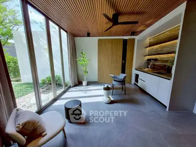 Modern living room with large windows, stylish furniture, and wooden ceiling.