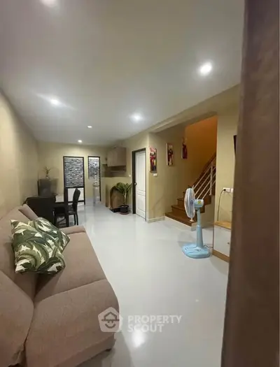 Spacious living room with modern decor and open layout leading to kitchen and staircase.