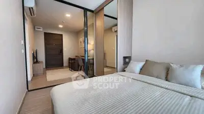 Modern bedroom with cozy bed and view into stylish living area, featuring sleek design and warm tones.