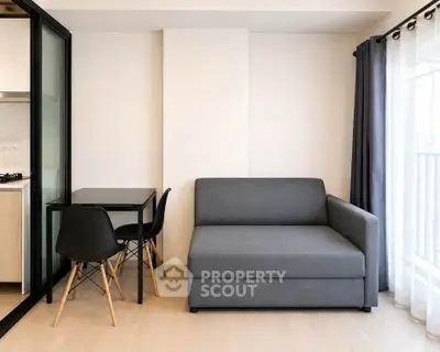 Modern living room with sleek gray sofa and dining area in stylish apartment.