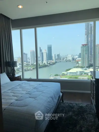 Luxurious bedroom with stunning city and river view from large window.