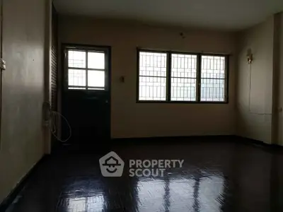Spacious empty room with large windows and dark flooring, ideal for customization.