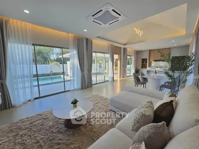 Luxurious open-plan living room with modern decor and pool view, featuring elegant furniture and natural light.