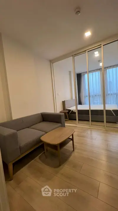 Modern living room with wooden flooring and glass partition leading to bedroom
