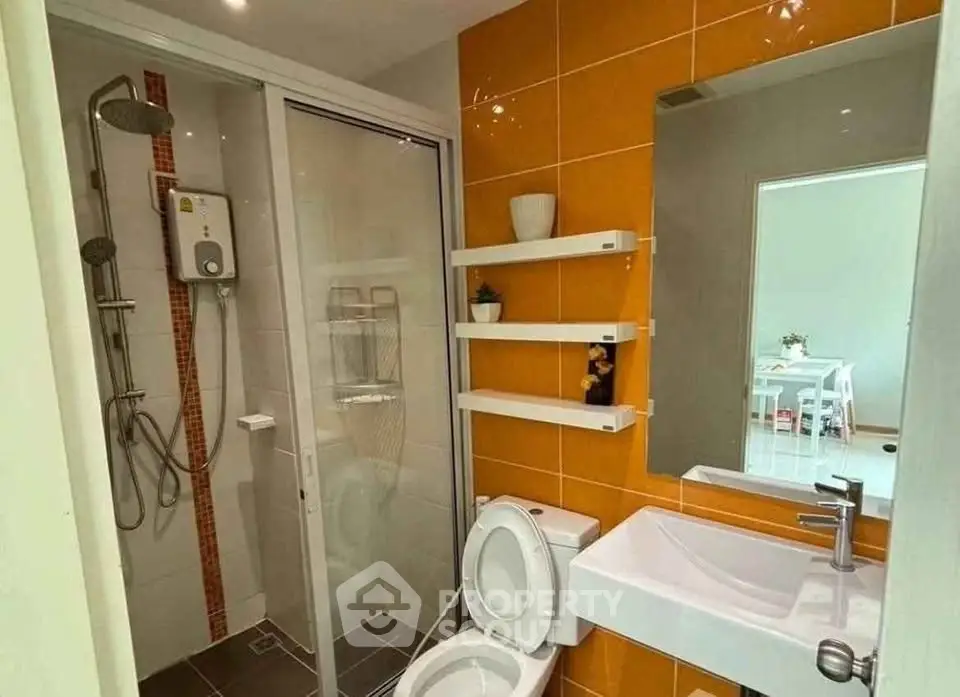 Modern bathroom with shower and orange accent tiles in a stylish apartment.