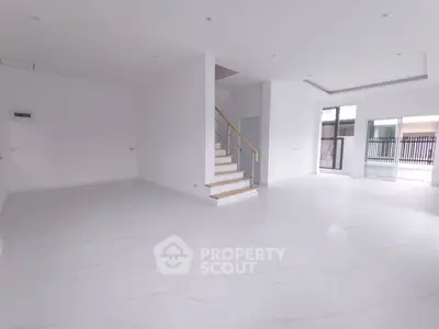 Spacious modern living room with elegant staircase and large windows