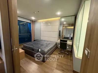 Modern bedroom with sleek design, featuring a large bed, wooden flooring, and a stylish work desk by the window.