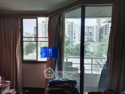 Spacious room with large windows offering a city view and access to a small balcony.