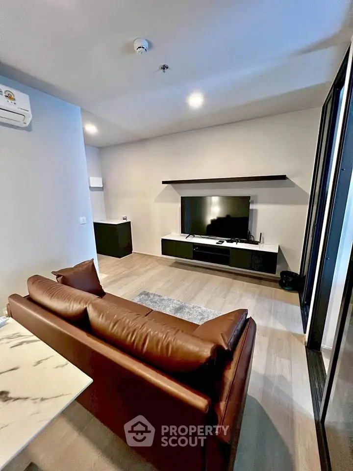 Modern living room with sleek design, featuring a leather sofa and wall-mounted TV, perfect for relaxation.