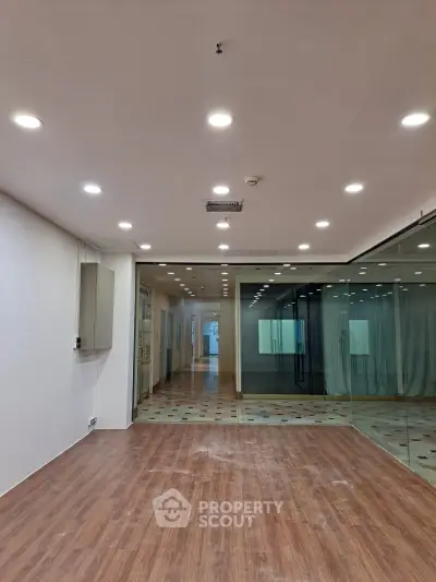 Spacious commercial interior with modern lighting and glass partitions, ideal for office or retail use.