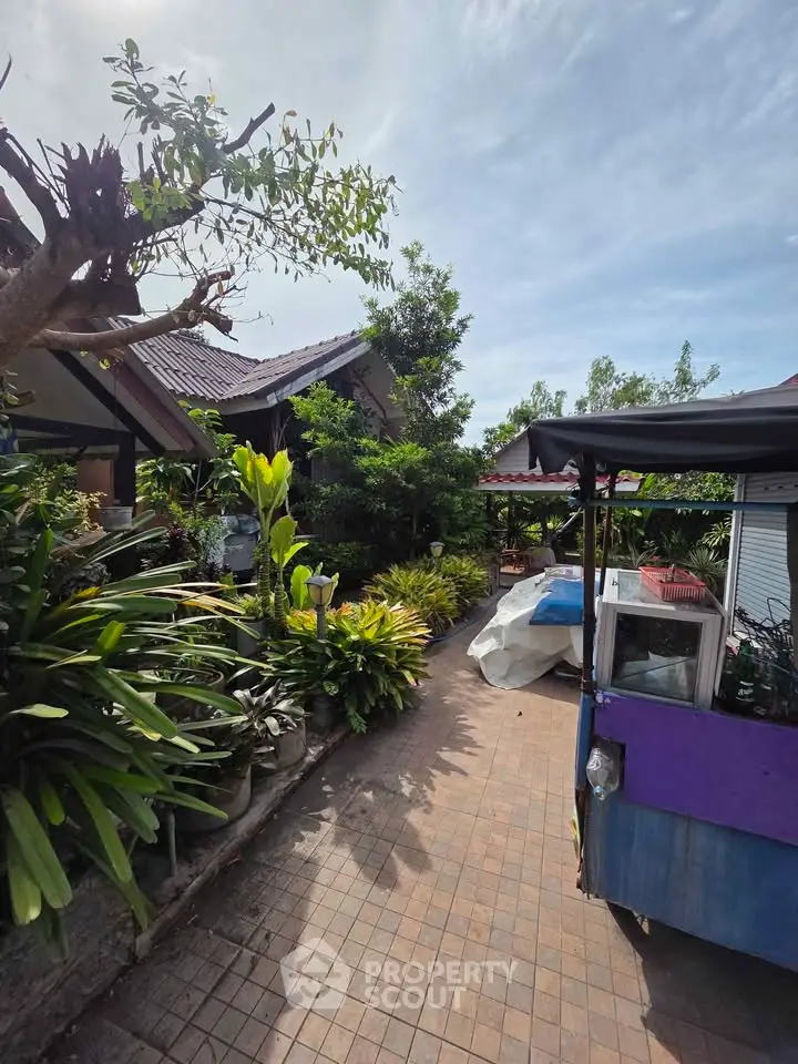 Charming garden pathway leading to a cozy home surrounded by lush greenery.