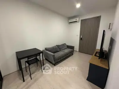 Modern living room with gray sofa, dining table, and TV in a cozy apartment.