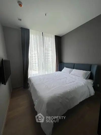 Modern bedroom with large window and stylish bed in a contemporary apartment.
