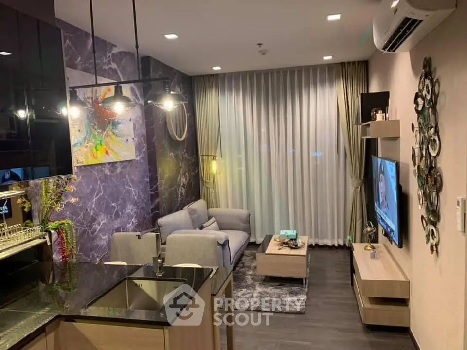 Modern living room with stylish decor and open kitchen layout, featuring a cozy seating area and contemporary lighting.