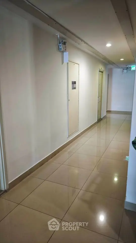 Modern apartment corridor with polished tile flooring and bright lighting.