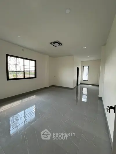 Spacious empty room with glossy tiled floor and large windows