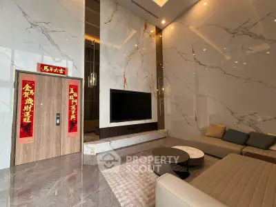 Luxurious living room with marble walls and modern furniture, featuring a large flat-screen TV.