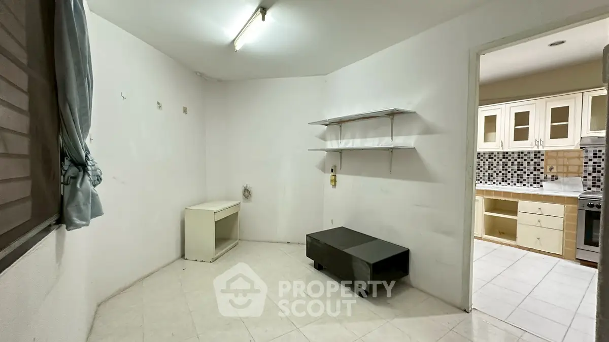 Spacious room with tiled floor and adjacent kitchen, ideal for customization.