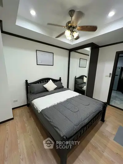 Modern bedroom with stylish decor and ceiling fan in a cozy apartment.