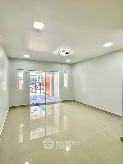Spacious and bright living room with glossy tiled floors and large windows.