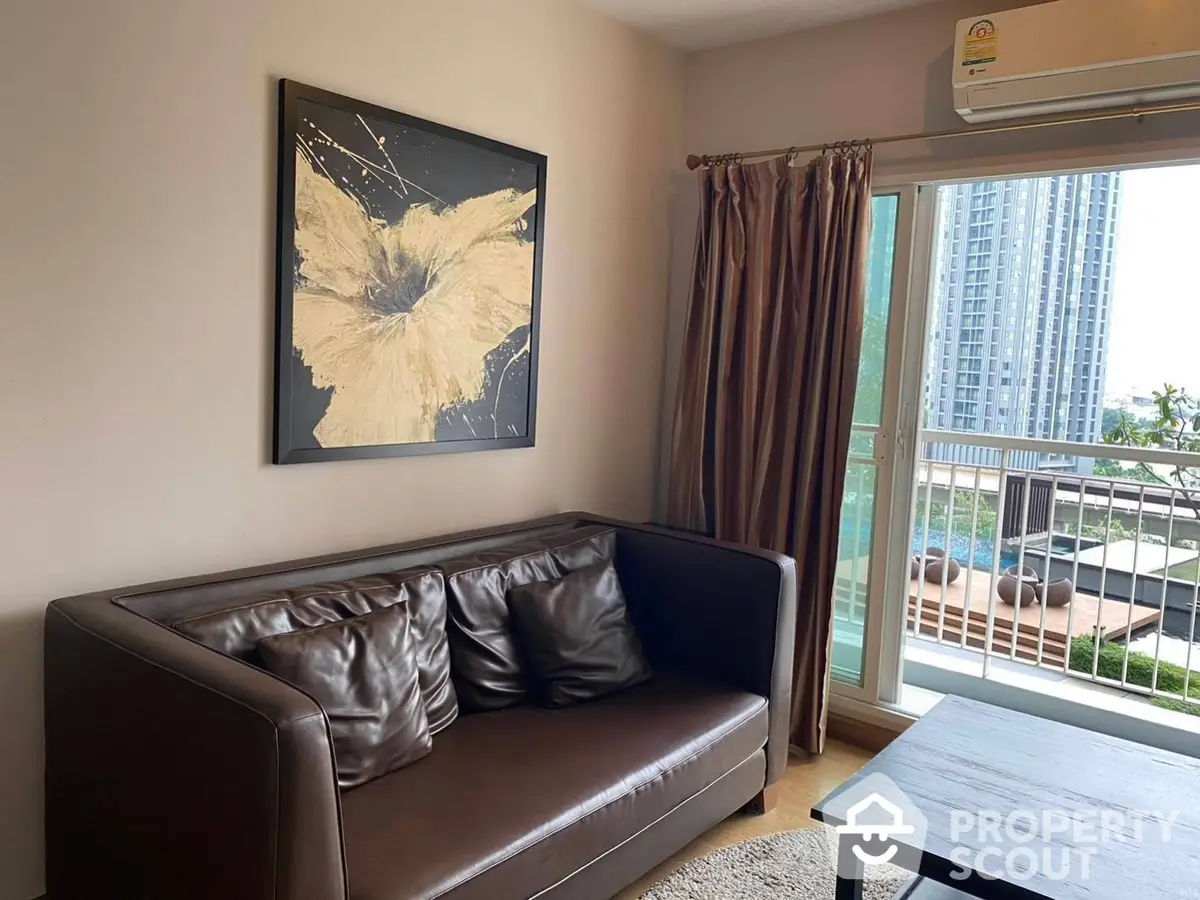 Cozy living room with a plush leather sofa, modern art, and access to a balcony with a city view, perfect for urban living.