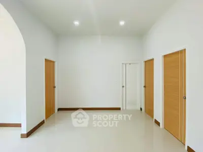 Spacious minimalist interior with multiple wooden doors and bright lighting