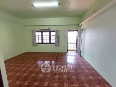 Spacious empty room with tiled floor and large window, ideal for customization.