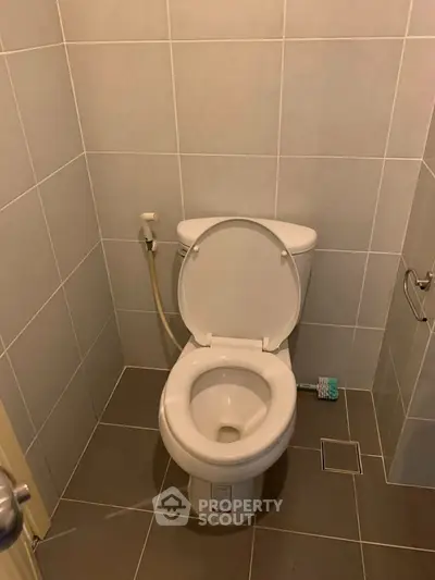 Modern bathroom with sleek tiled walls and floor, featuring a standard toilet setup.