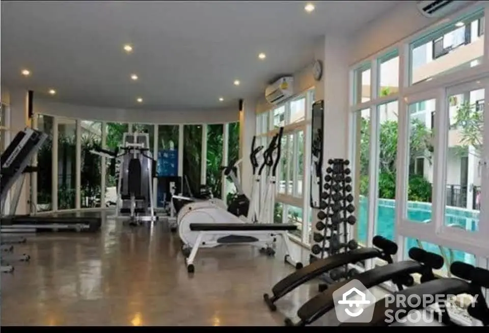 Modern gym with large windows and pool view in luxury apartment complex