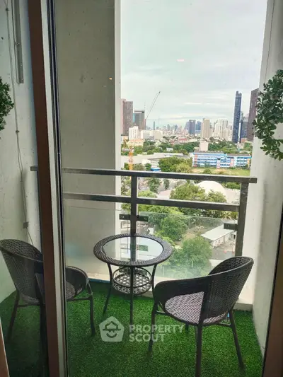 Charming balcony with city view, featuring cozy seating and lush artificial grass, perfect for relaxation.