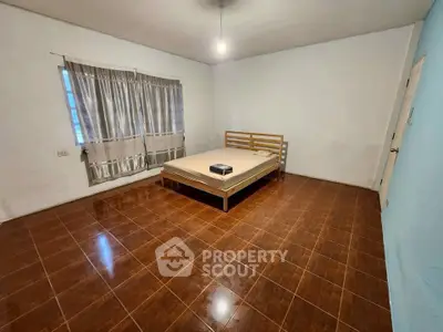 Spacious bedroom with minimalist decor and large window for natural light.