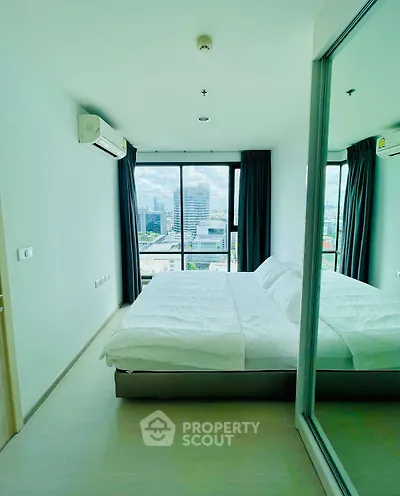 Modern bedroom with city view, large window, and mirrored closet in a high-rise apartment.