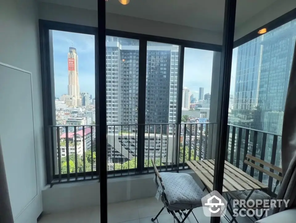 Modern balcony with city view and cozy seating in high-rise apartment