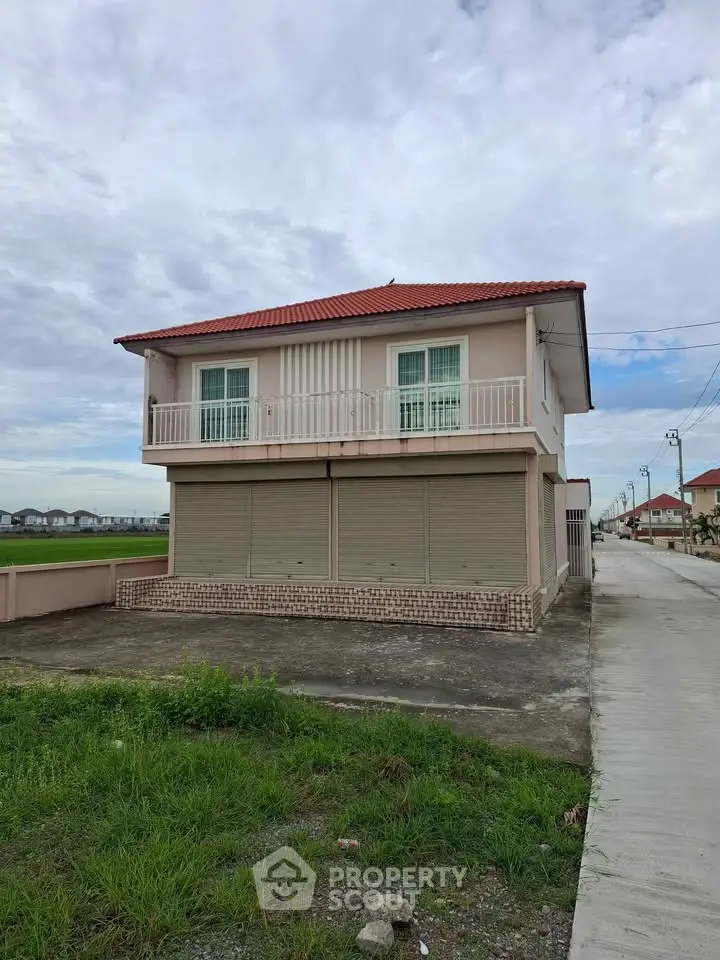 Charming two-story house with red-tiled roof and spacious balcony in a serene neighborhood.